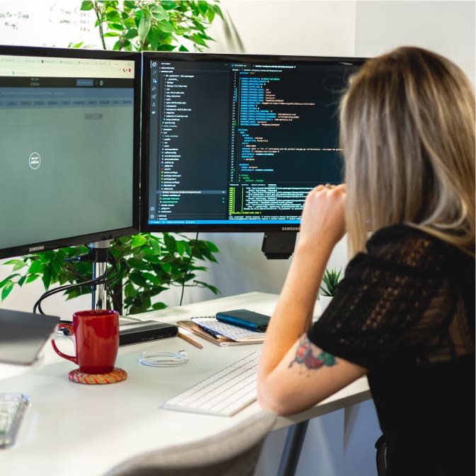 developer Rach sat at desk working on code open on her screen